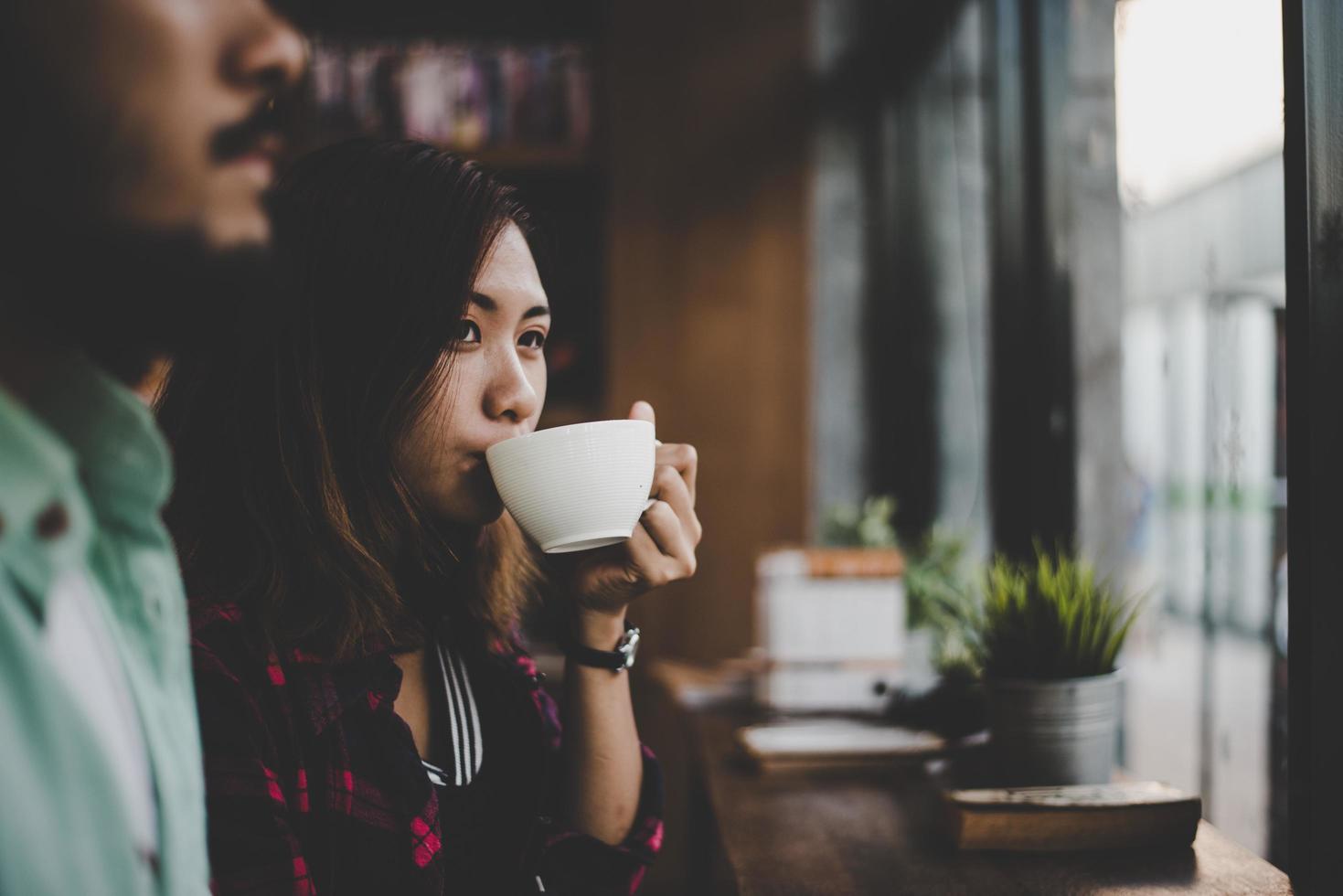 Hipster couple on vacation sitting in indoors cafe drinking coffee photo