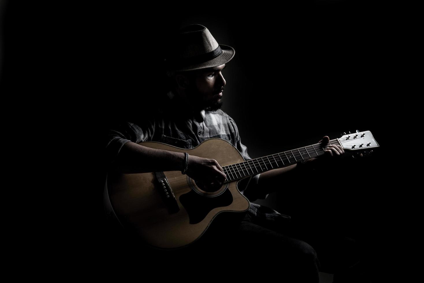 Young hipster guitarist on dark background photo