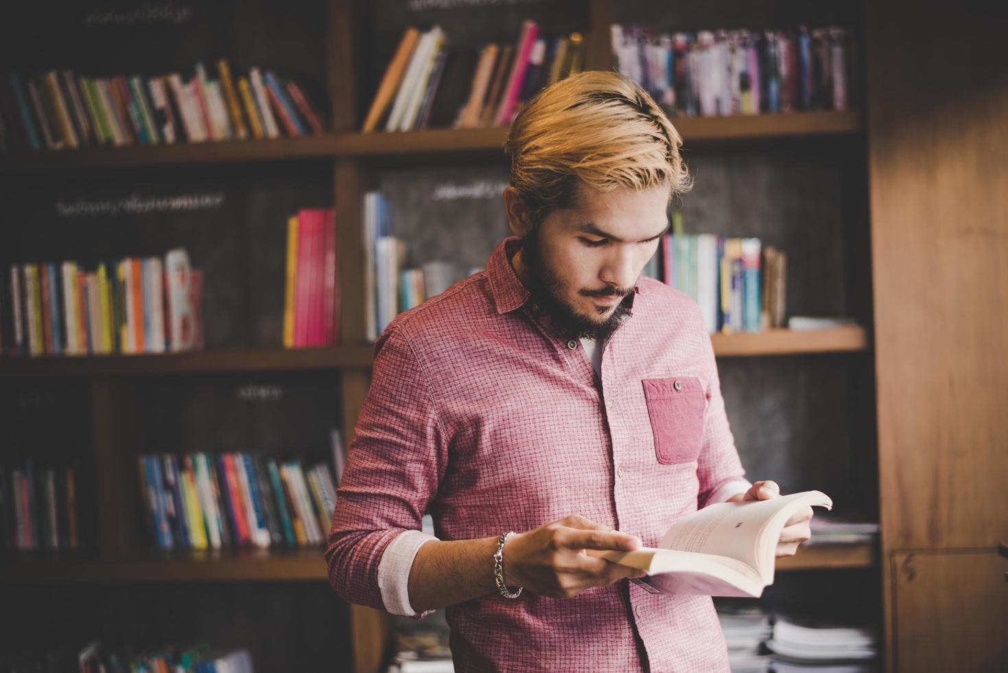 Joven hipster barbudo leyendo un libro en un café foto