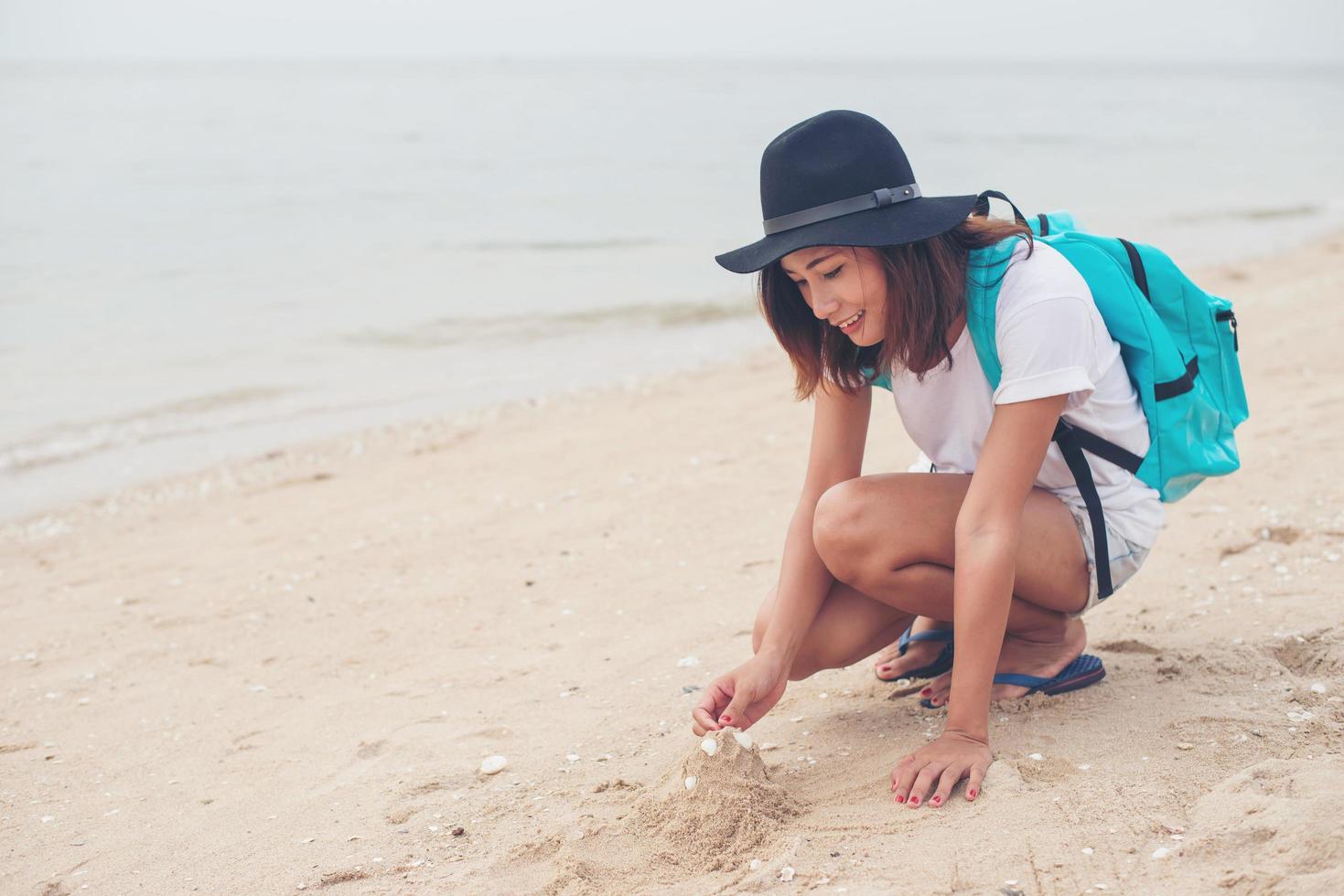 Young woman with a backpack sitting on the beach photo