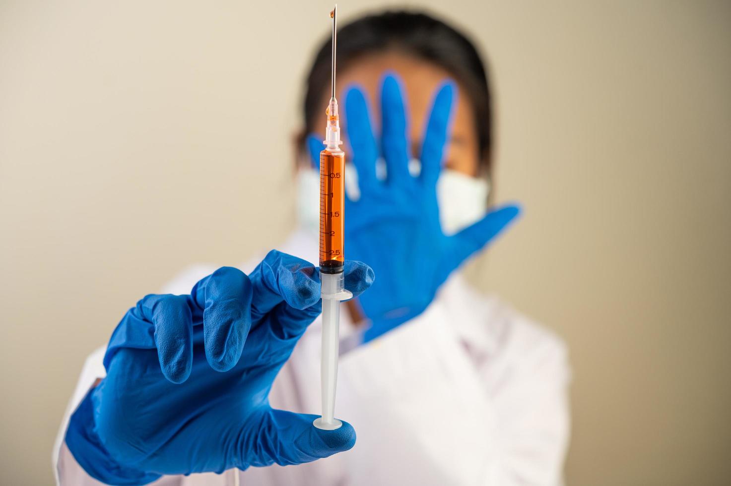 Scientist wearing protective masks and gloves holding a syringe with a vaccine to prevent covid-19 photo