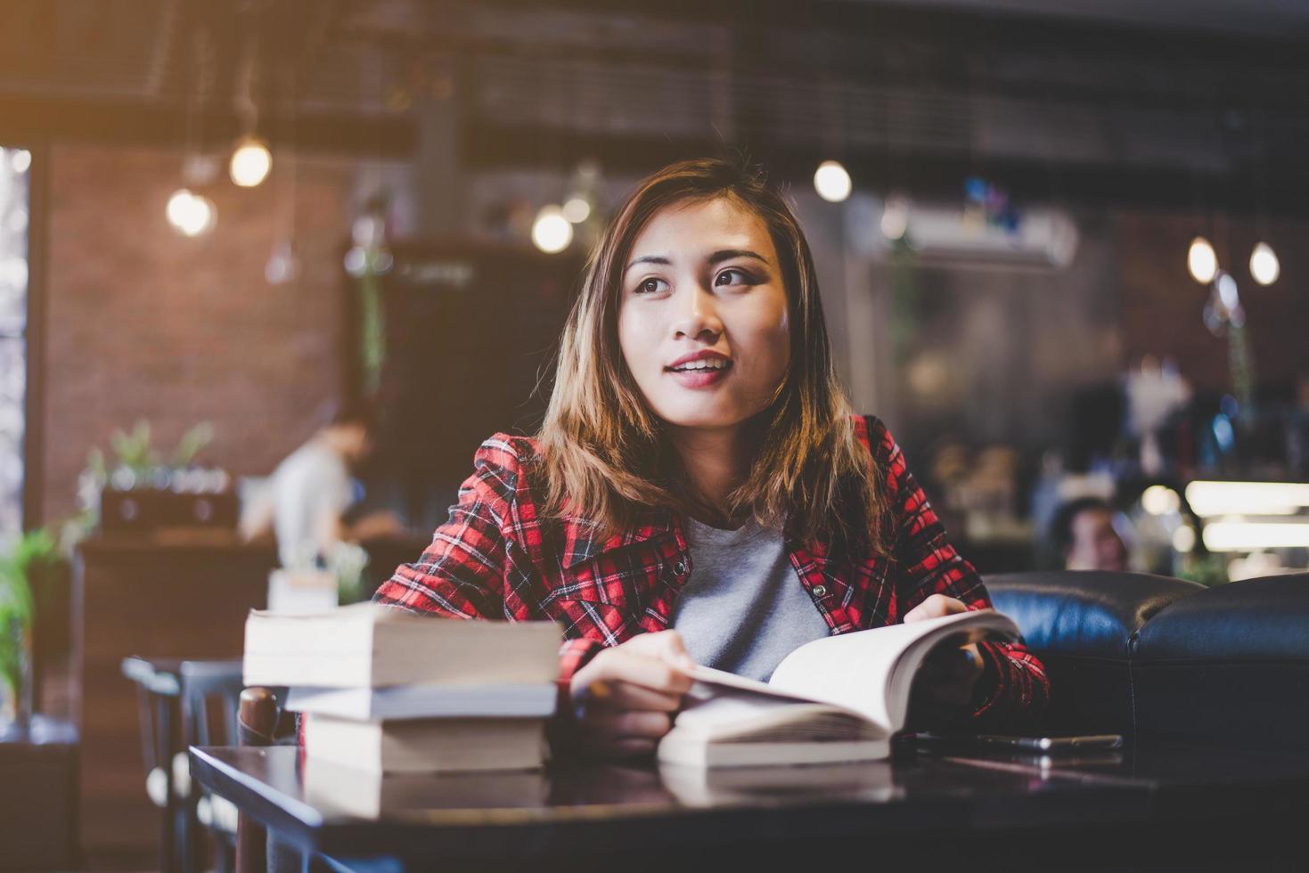 Hipster teenager sitting and enjoying a book at a cafe photo