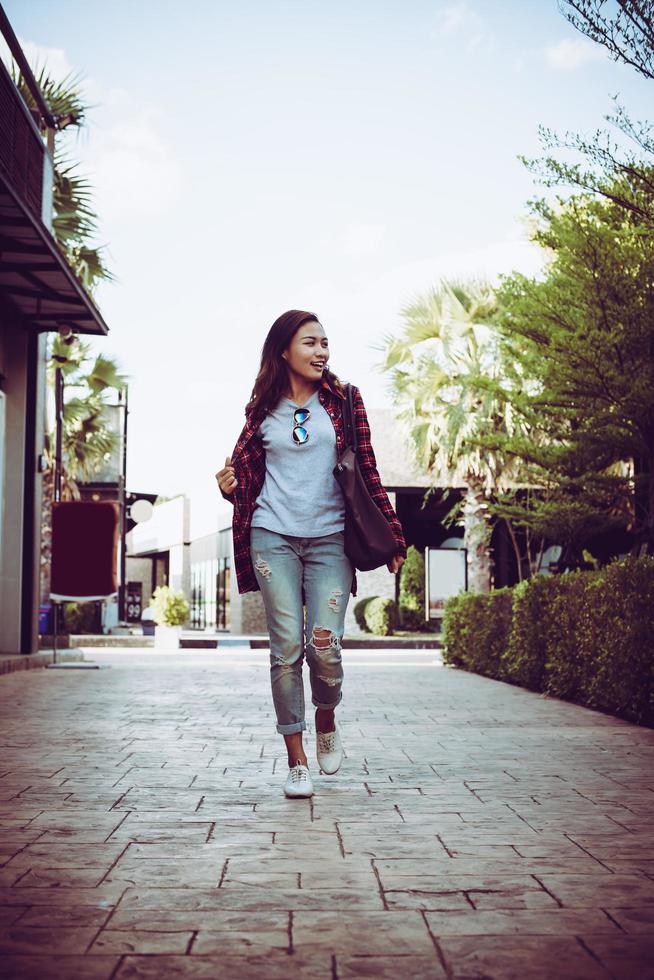 Portrait of young stylish hipster woman walking on urban street, smiling enjoy weekends. Vintage toned. photo