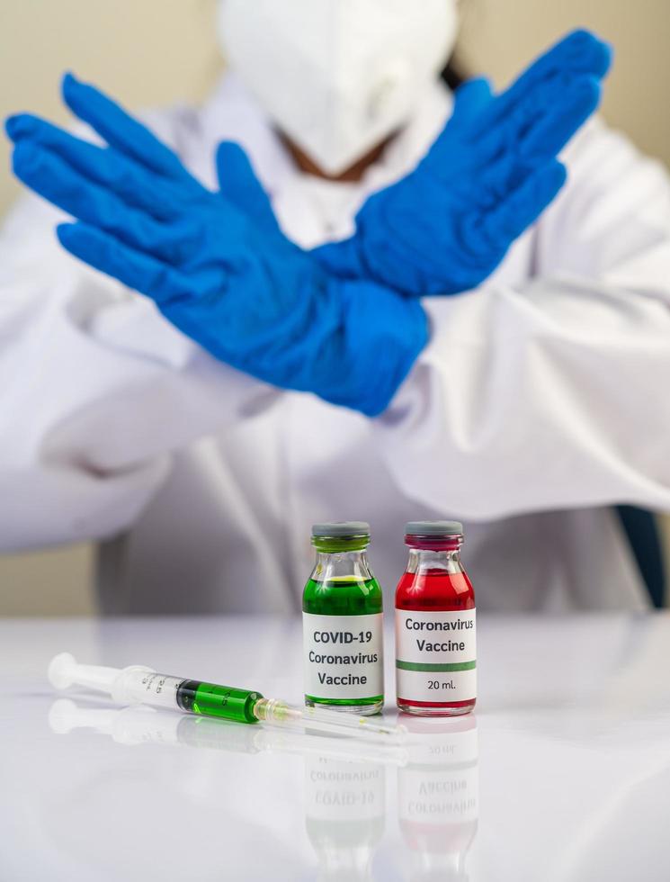 Scientist wearing blue glove makes hands at unacceptable vaccine photo