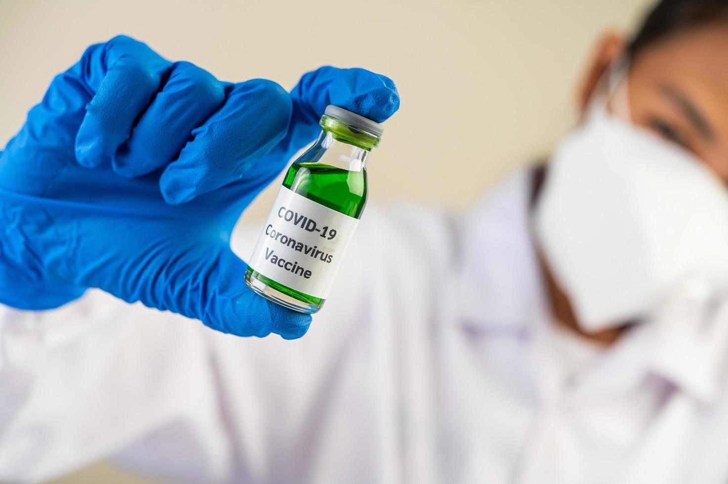 A scientist wearing mask and gloves carries vials with vaccines to protect against covid-19 photo