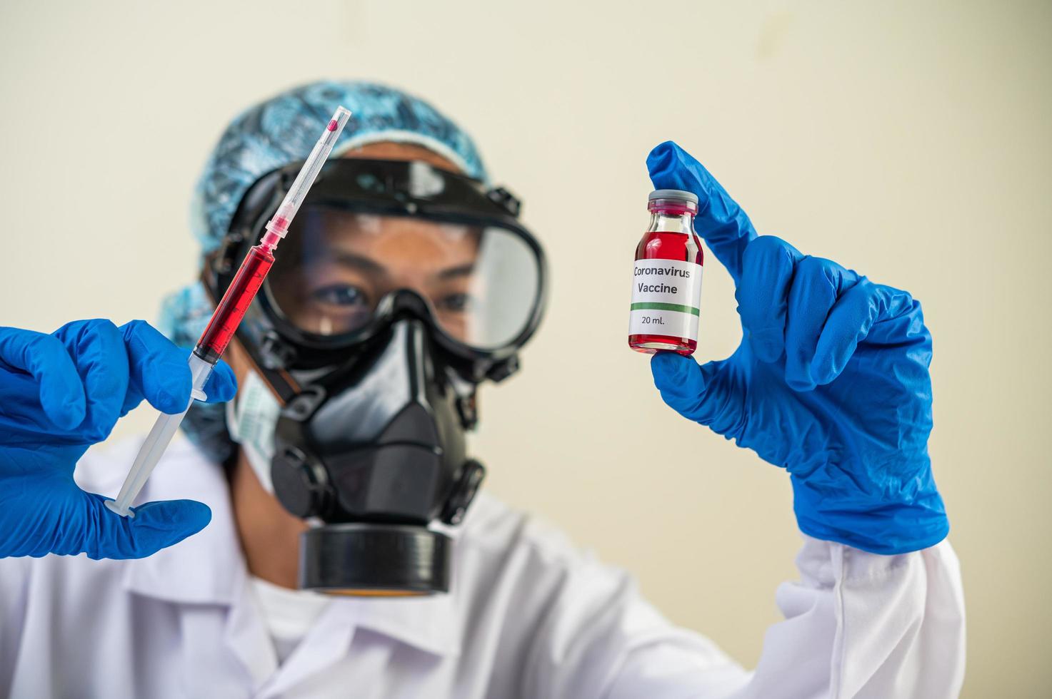 científico con máscaras protectoras y guantes sosteniendo una jeringa con una vacuna para prevenir la covid-19 foto