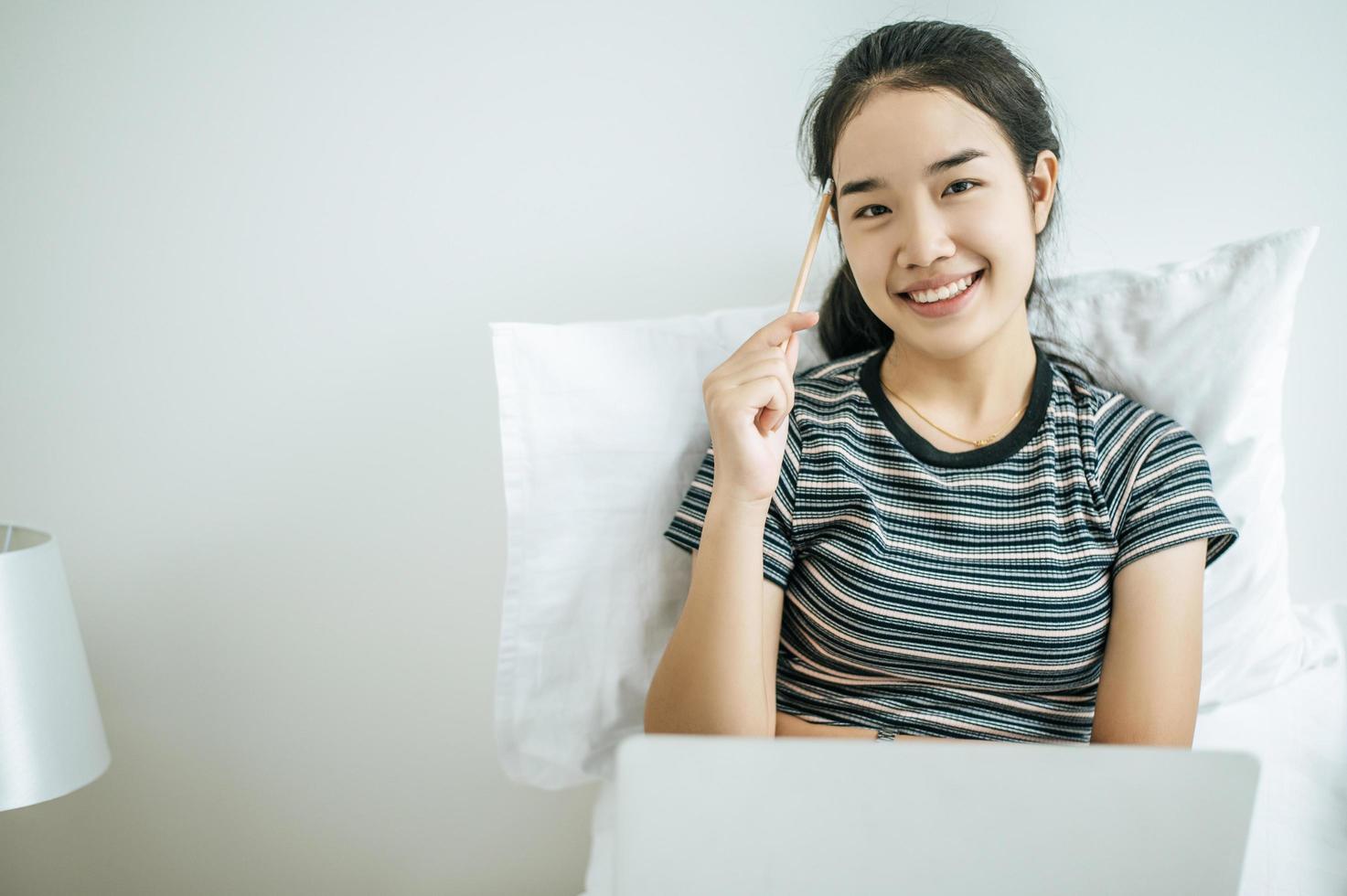 Mujer joven jugando en su computadora portátil y sosteniendo un lápiz foto