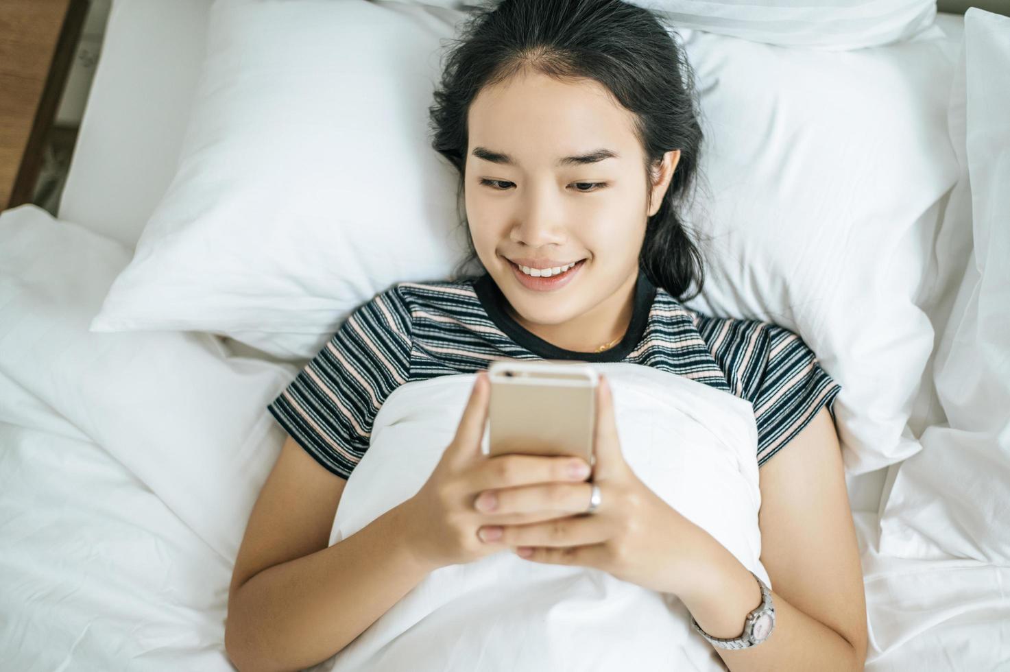 mujer joven, utilizar, ella, smartphone, en cama foto