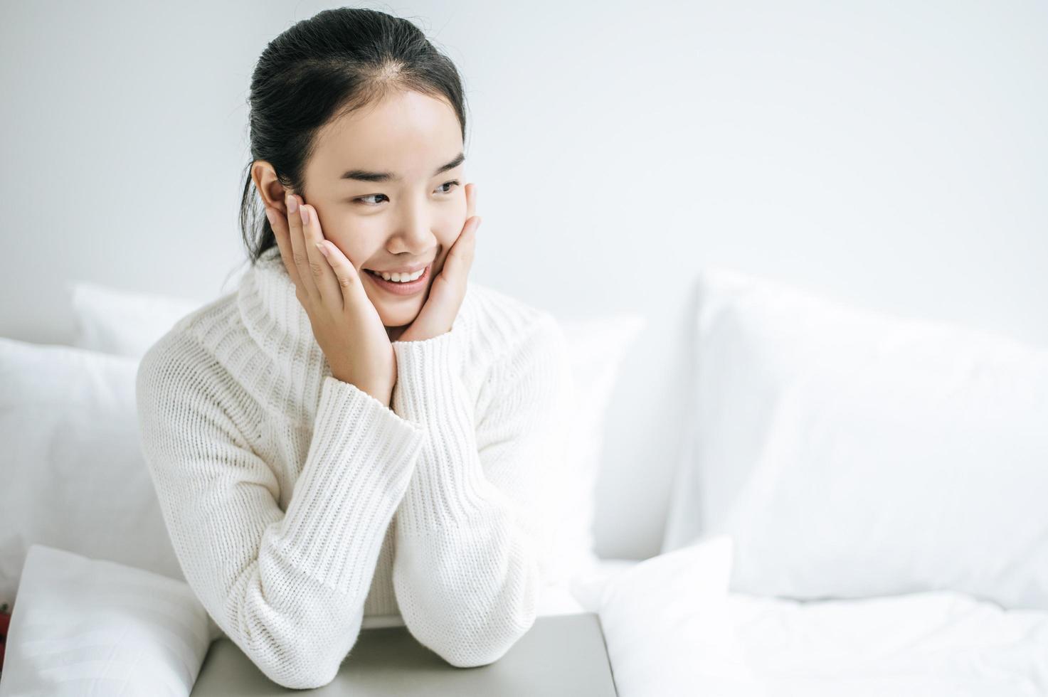 Young woman sitting on her bed with hands touching cheeks photo