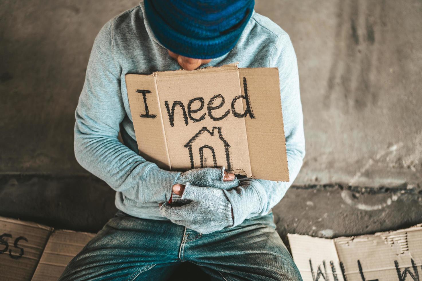 Beggars sitting under the bridge with a sign photo