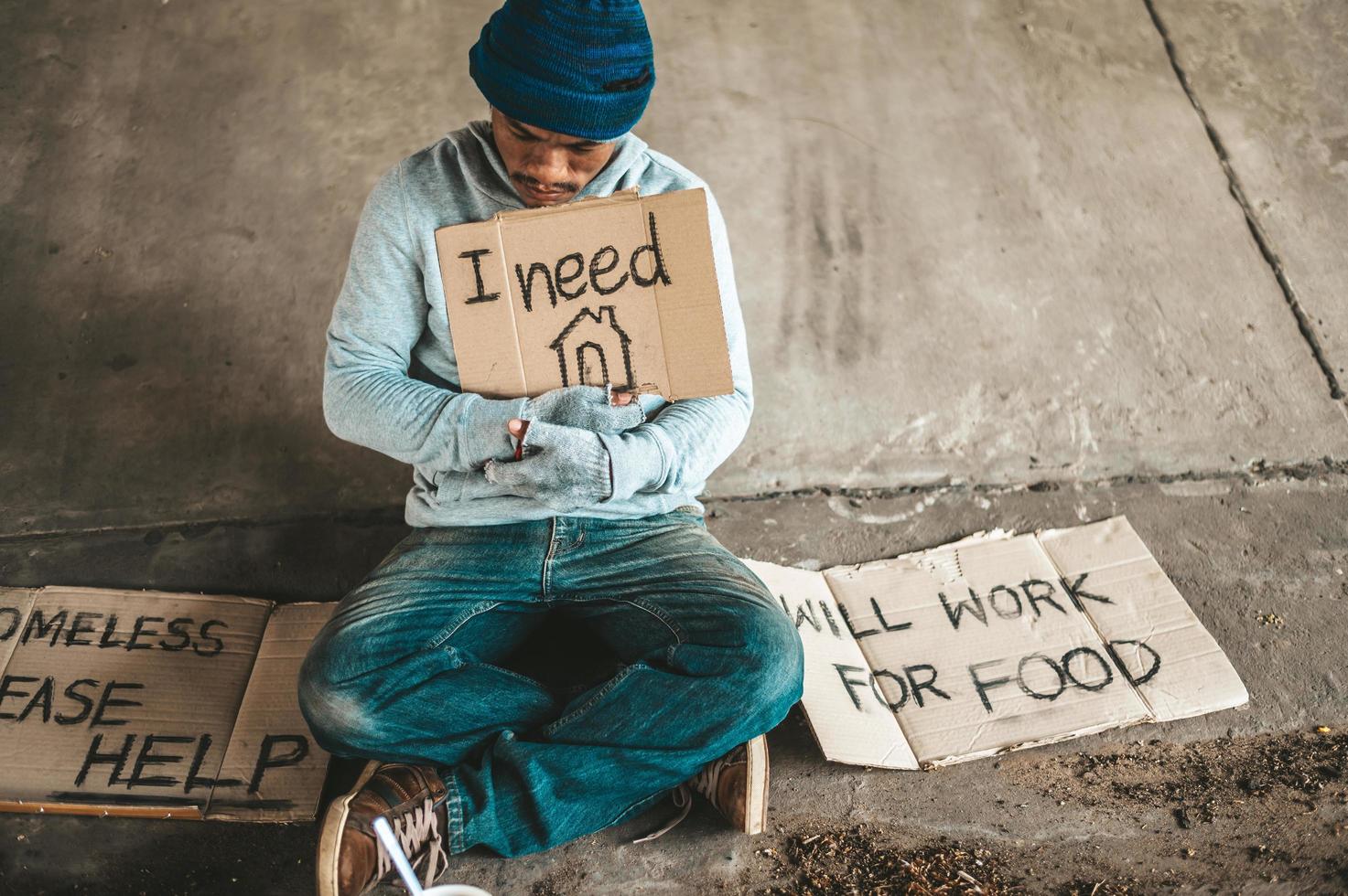Beggars sitting under the bridge with a sign photo
