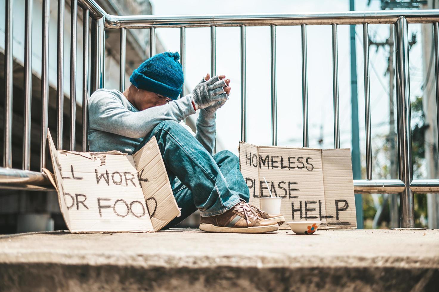 Man sitting begging on an overpass photo