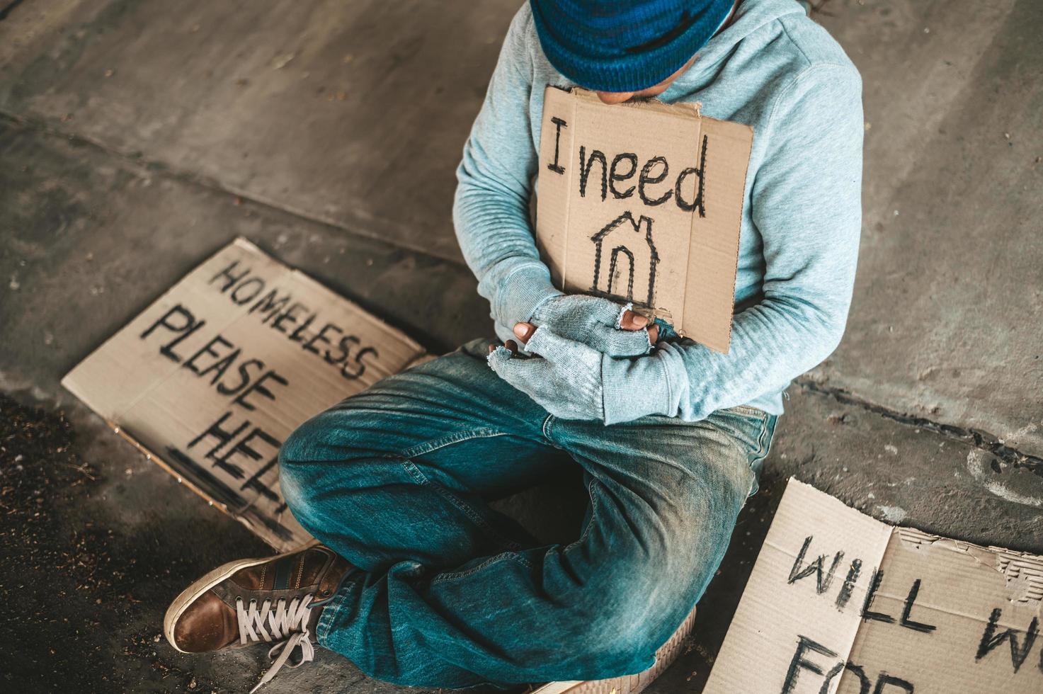 Beggars sitting under the bridge with a sign photo