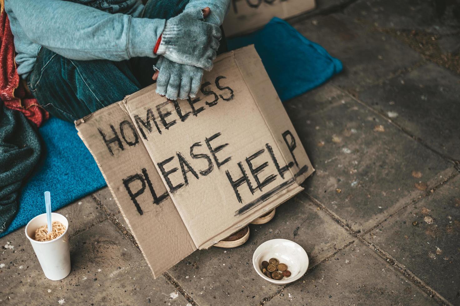 Man sits beside the street with a homeless message photo