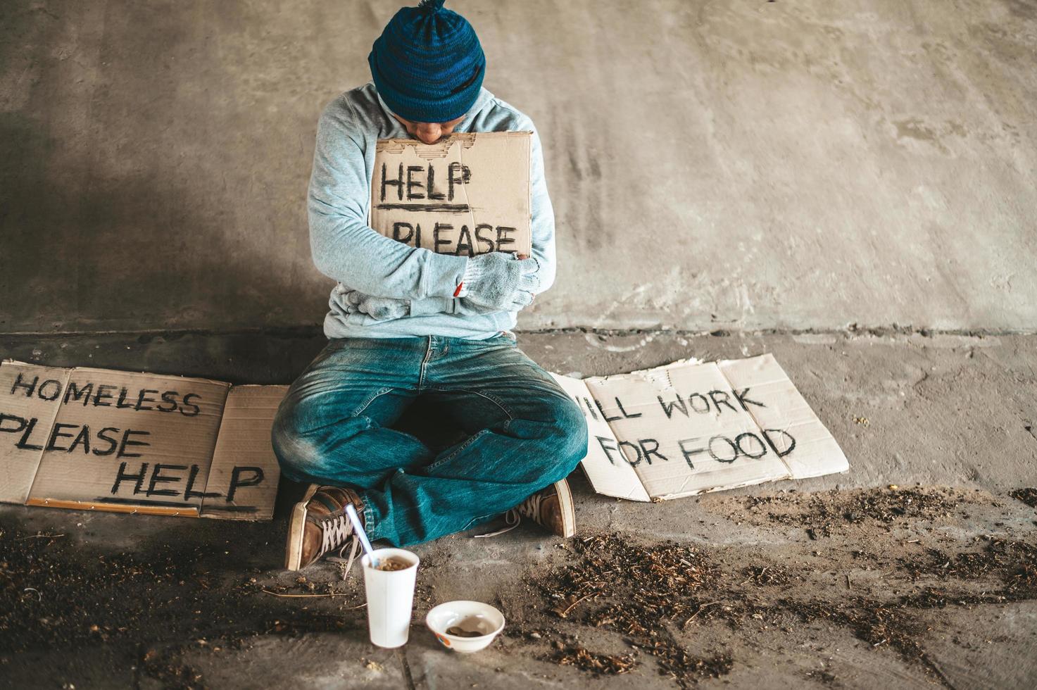 Beggars sitting under the bridge with a sign photo