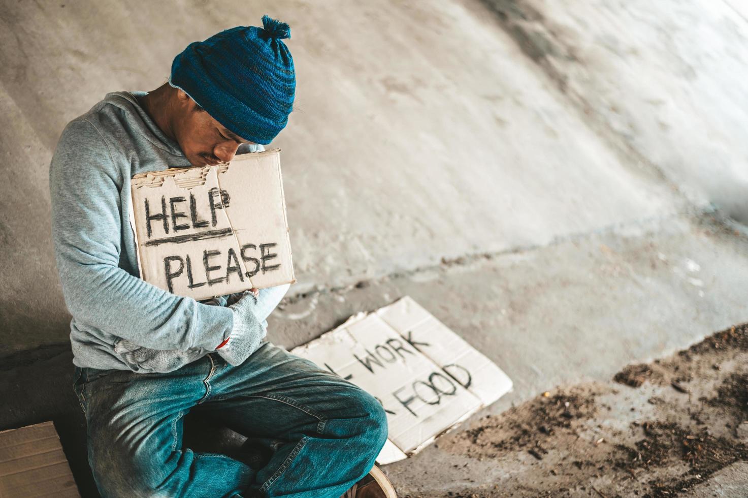 Beggars sitting under the bridge with a sign photo
