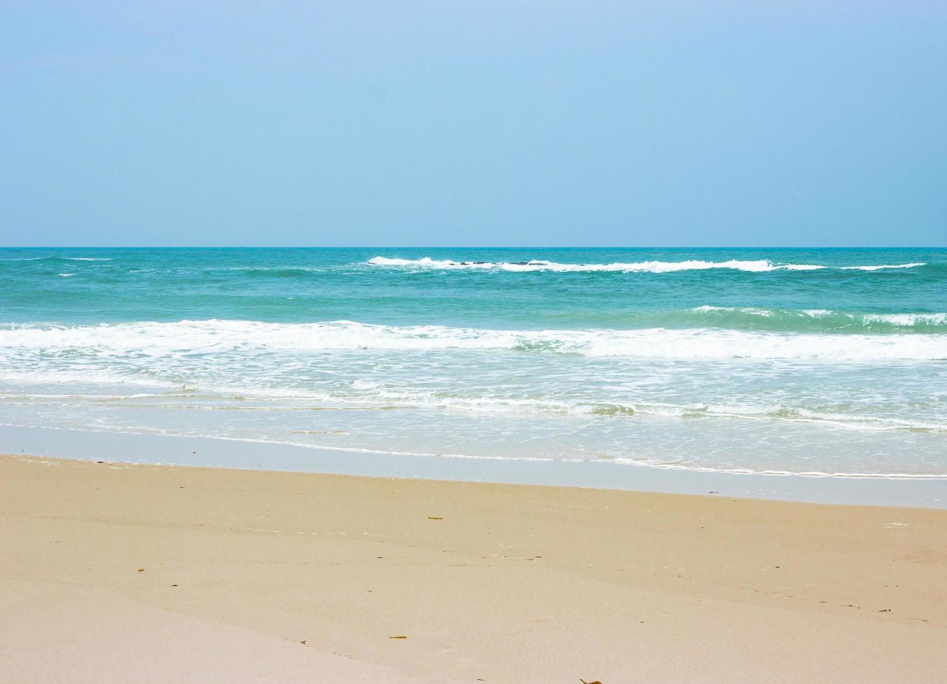 Ocean waves on beach with clear blue sky photo