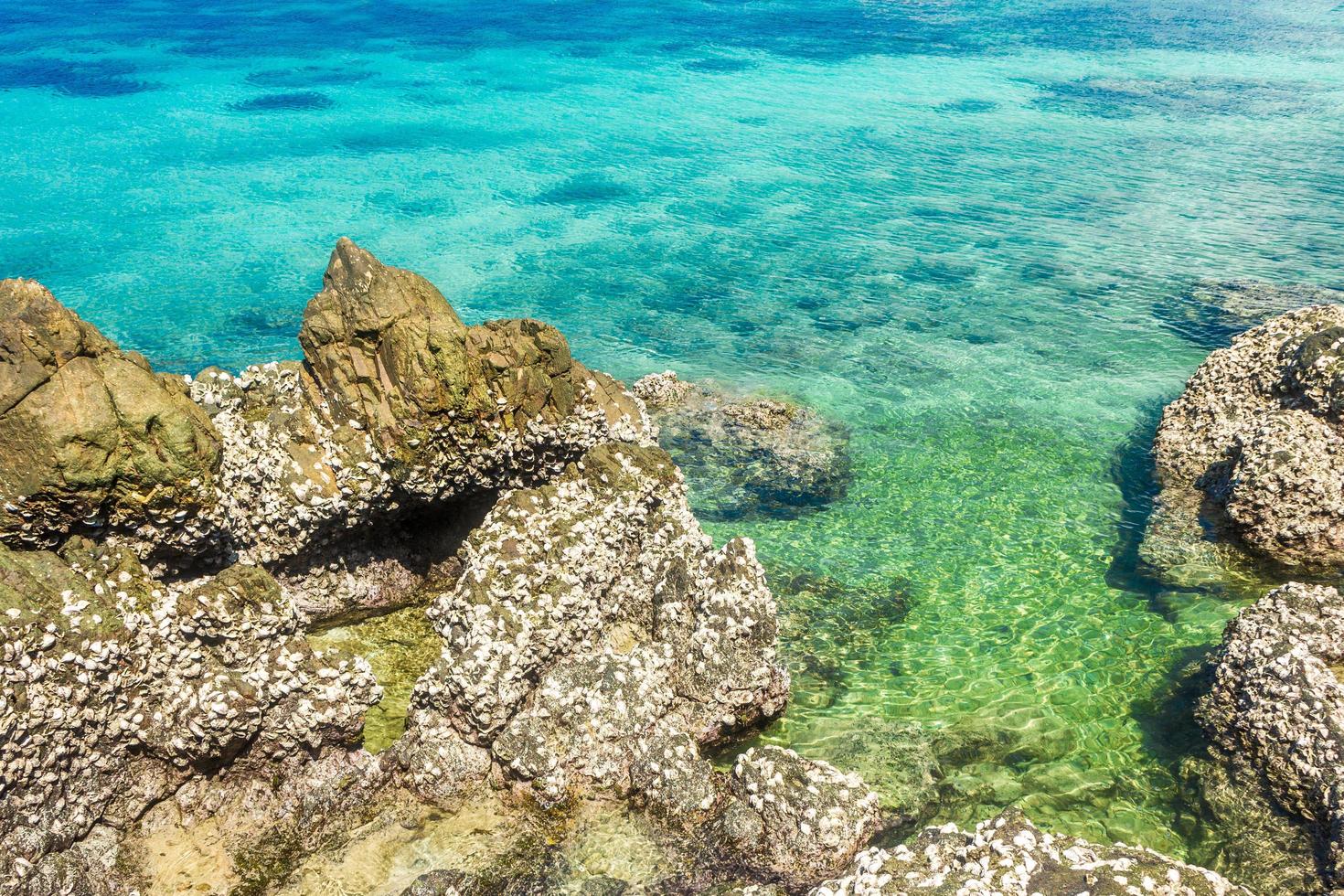 Tropical island rock with clear blue water photo