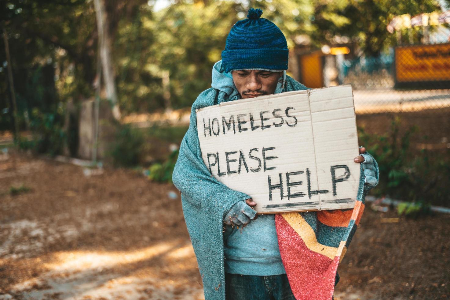 Beggar stands on the street with homeless messages please help photo