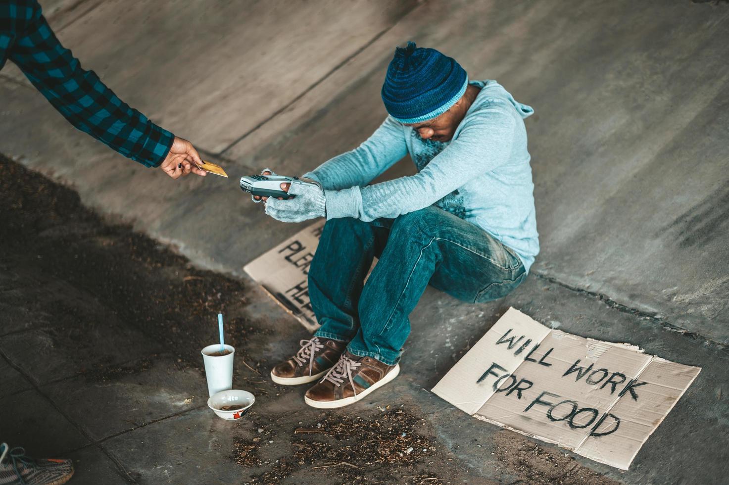 Beggars sitting under the bridge with a credit card swipe machine photo
