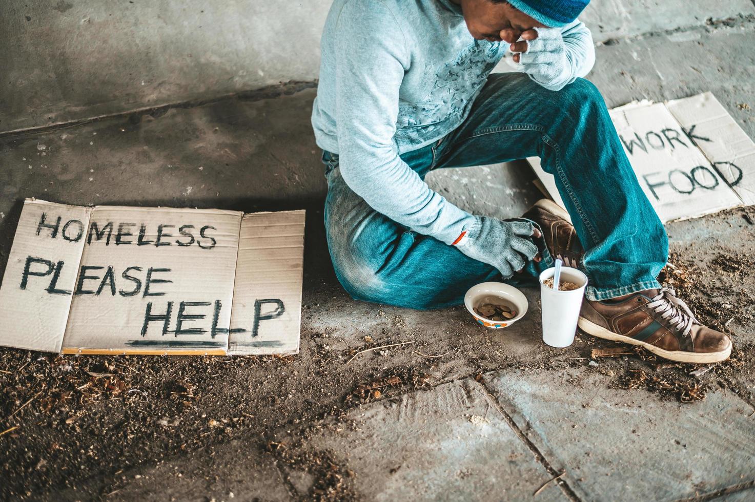 Begging under the bridge with a cup containing coins and instant noodles photo