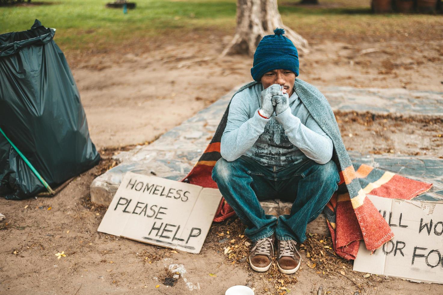 A beggar sitting outside with please help signs photo