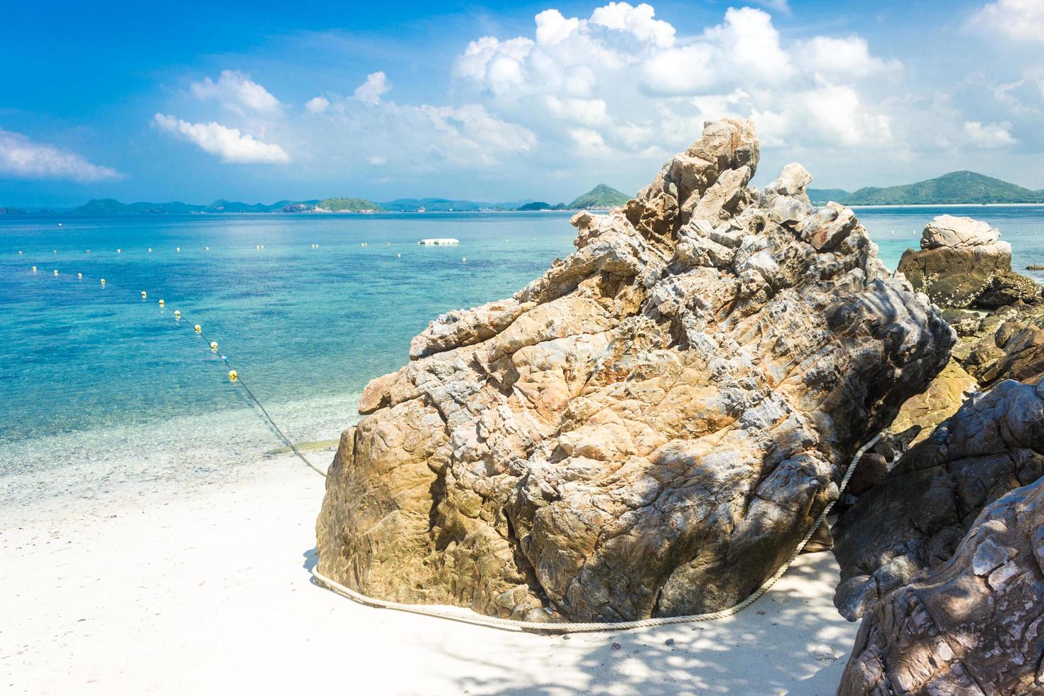 Tropical island rock on the beach with cloudy blue sky photo