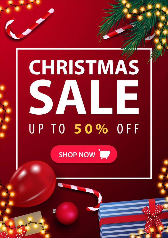 Christmas sale, up to 50 off, red vertical discount banner with presents, candy canes, Christmas tree branches and balloon on surface, top view vector