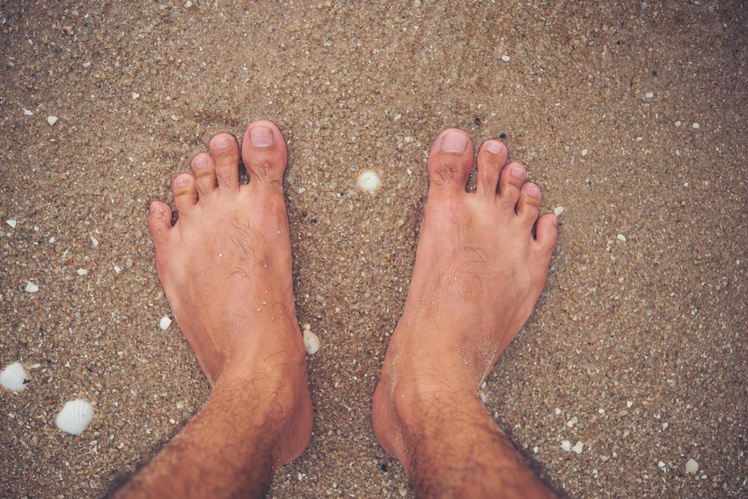 pies de hombre joven en la playa foto