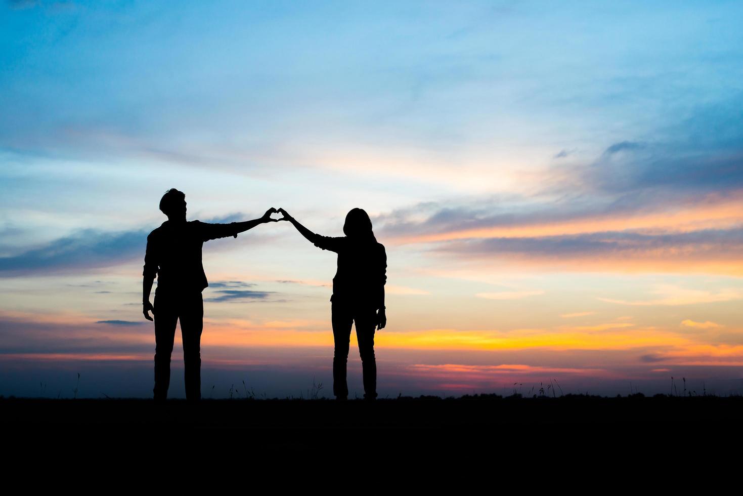 silueta, de, pareja joven, juntos, durante, ocaso foto