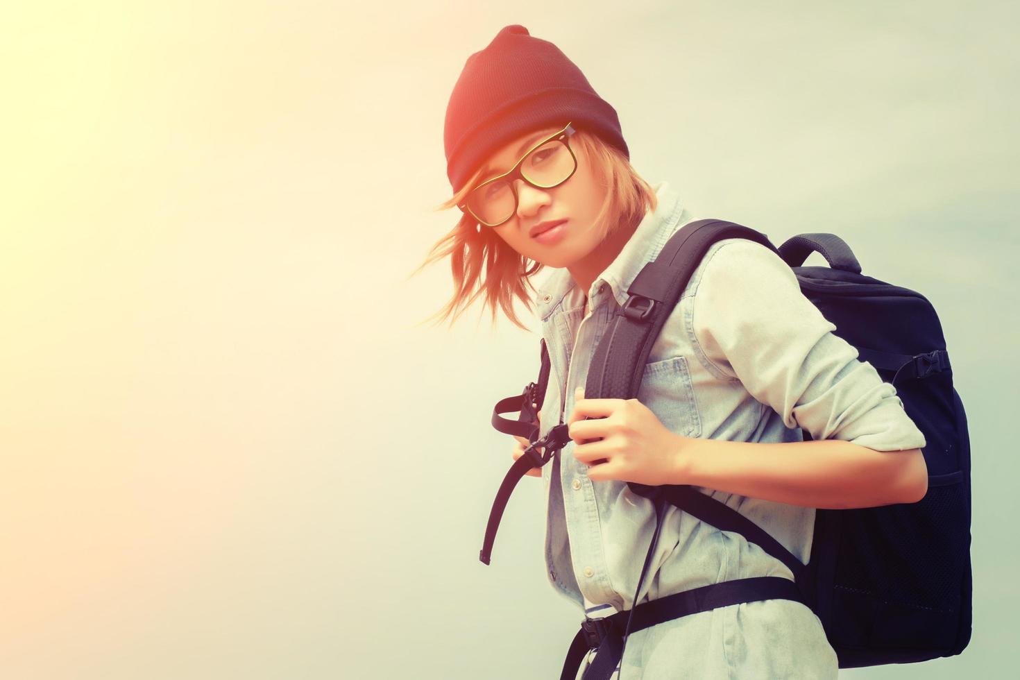 Adolescente con gafas, llevando una mochila para viajar foto