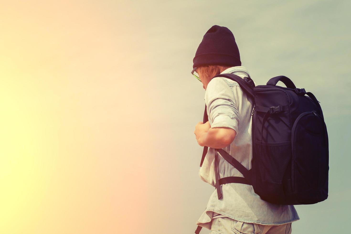 Adolescente con gafas, llevando una mochila para viajar foto