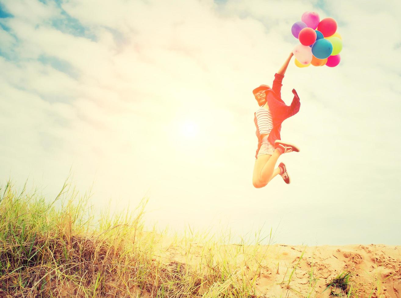 hermosa niña saltando con globos en la playa foto