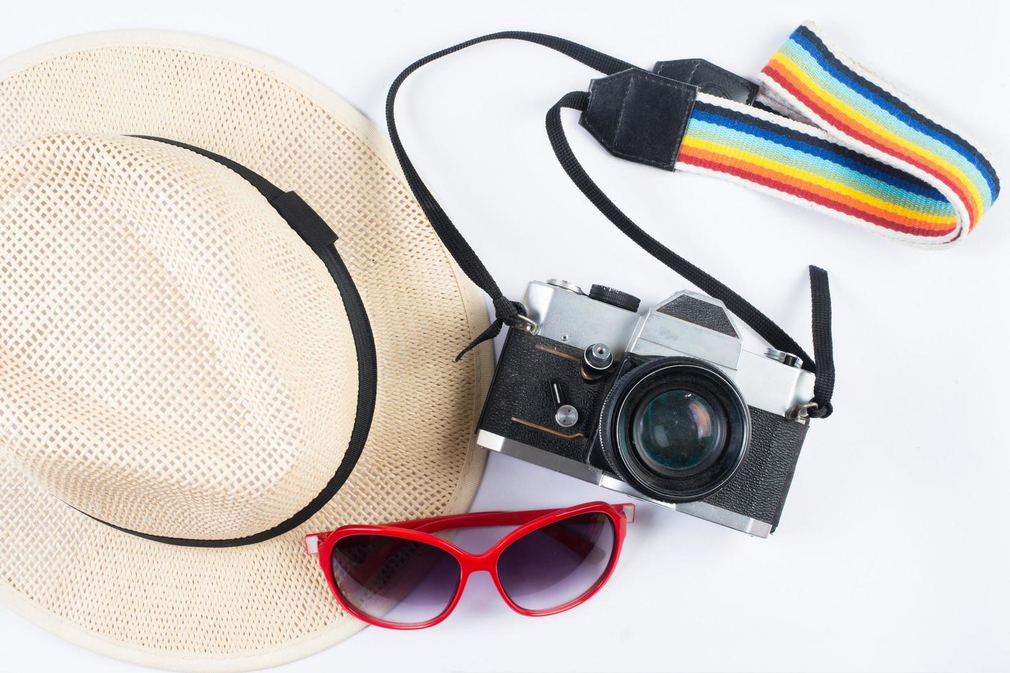 Sombrero, gafas de sol y cámara vintage aislado sobre un fondo blanco. foto