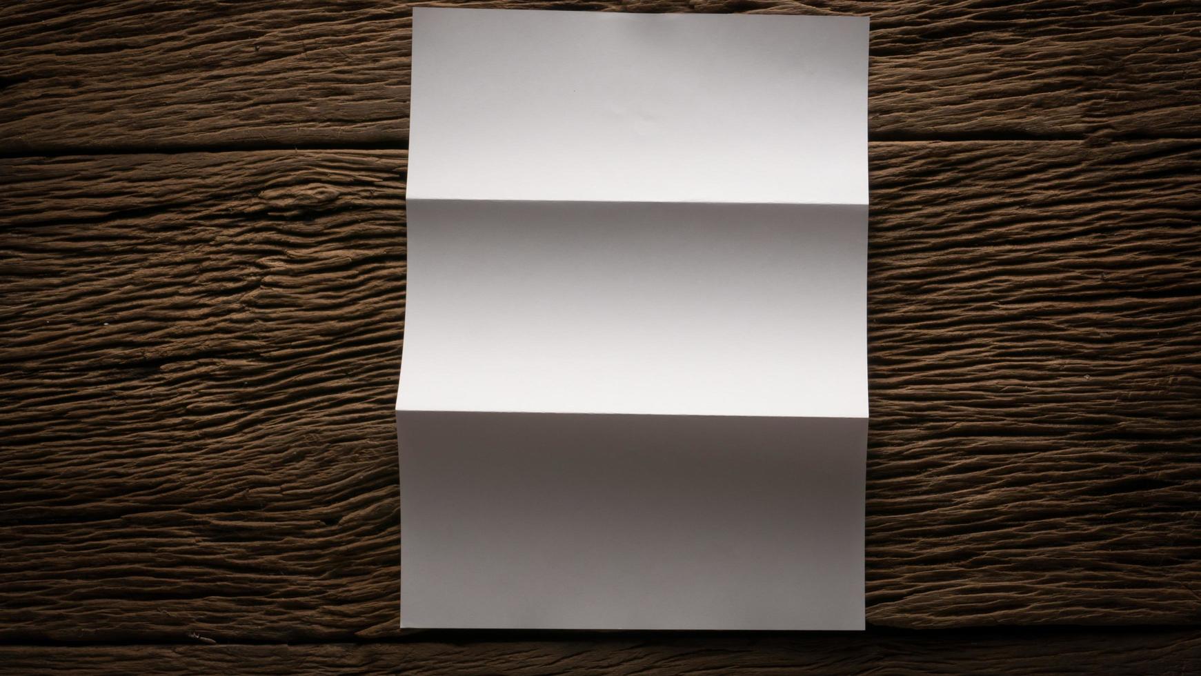 White blank folded paper on wooden table photo