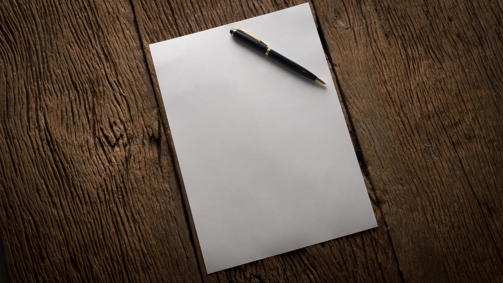 Blank sheet of paper and pen on a wooden table photo