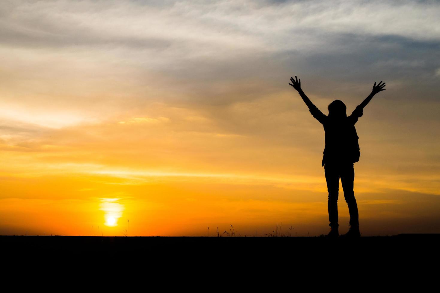 Hiker with a backpack relaxing and enjoying sunset photo