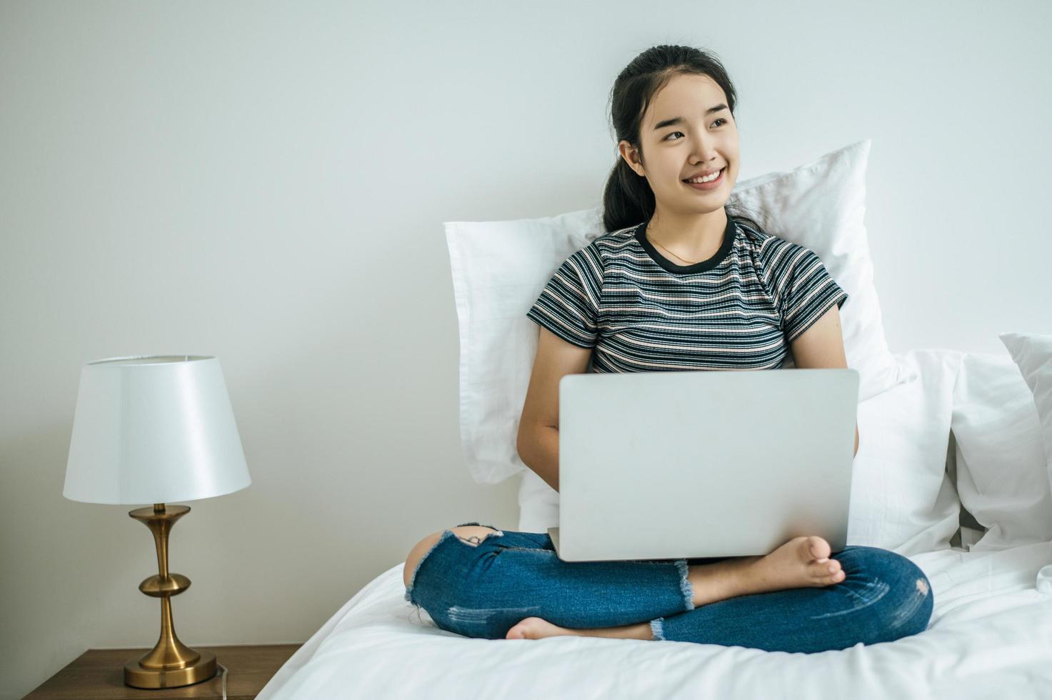 mujer joven, juego, en, ella, computadora portátil, en cama foto