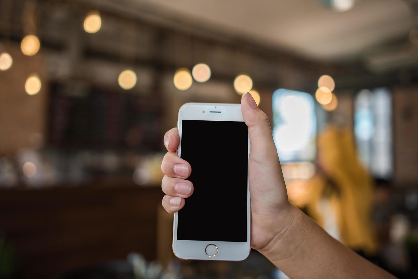 Hand holding a white mobile phone with blank black screen photo