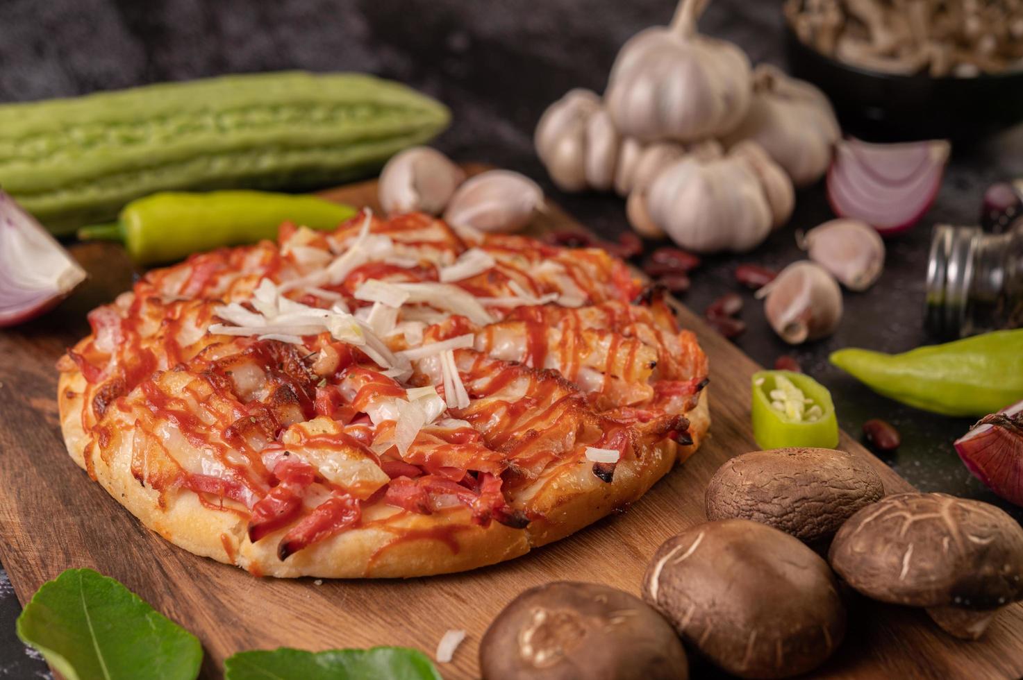 pizza en una tabla de madera con pimientos, ajo, chile y setas shiitake foto