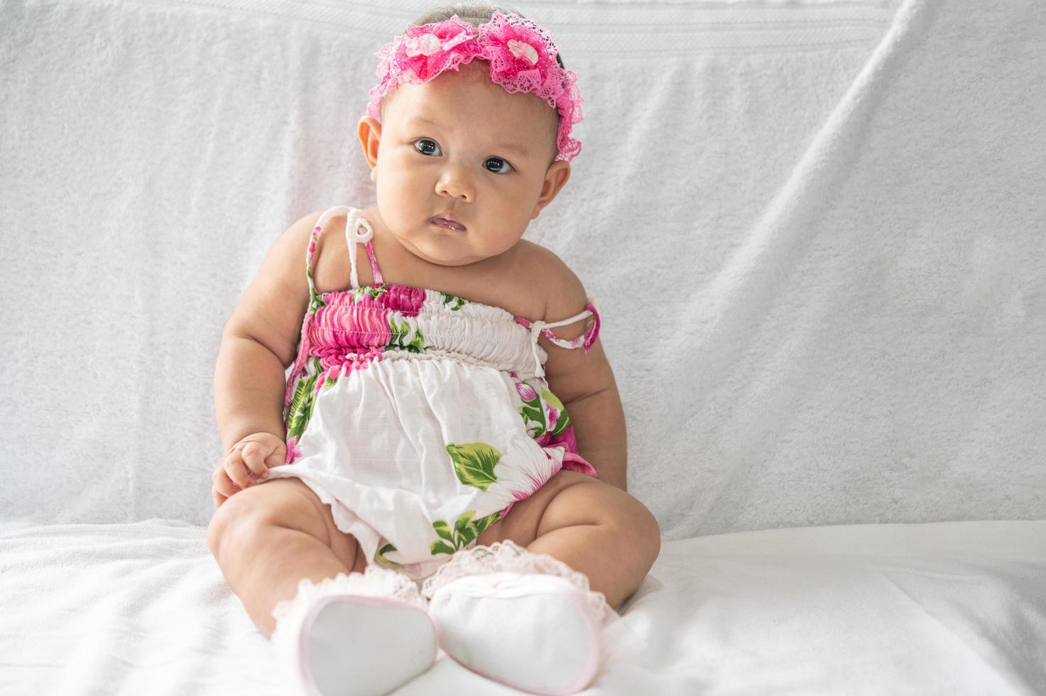 A baby learning to sit on a white bed photo