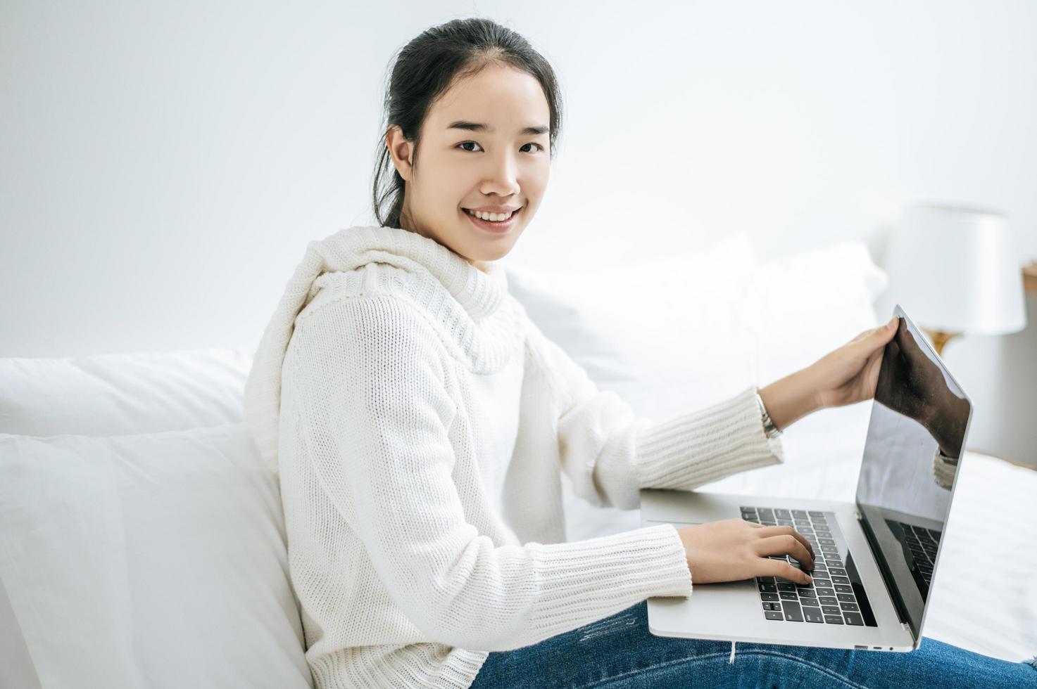 Young woman wearing a white shirt playing on her laptop photo