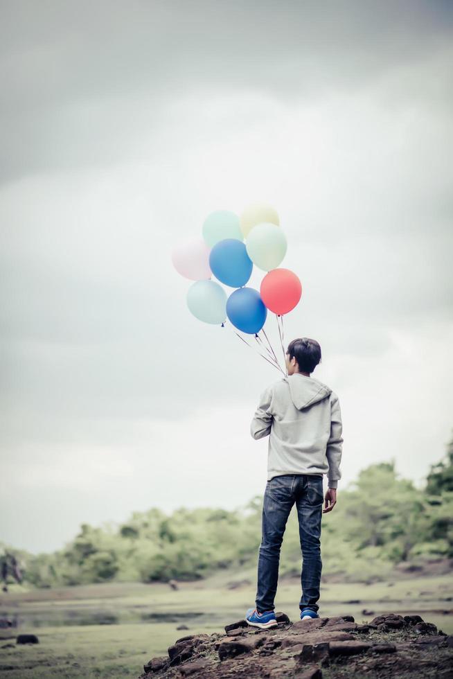 joven sosteniendo globos de colores en la naturaleza foto