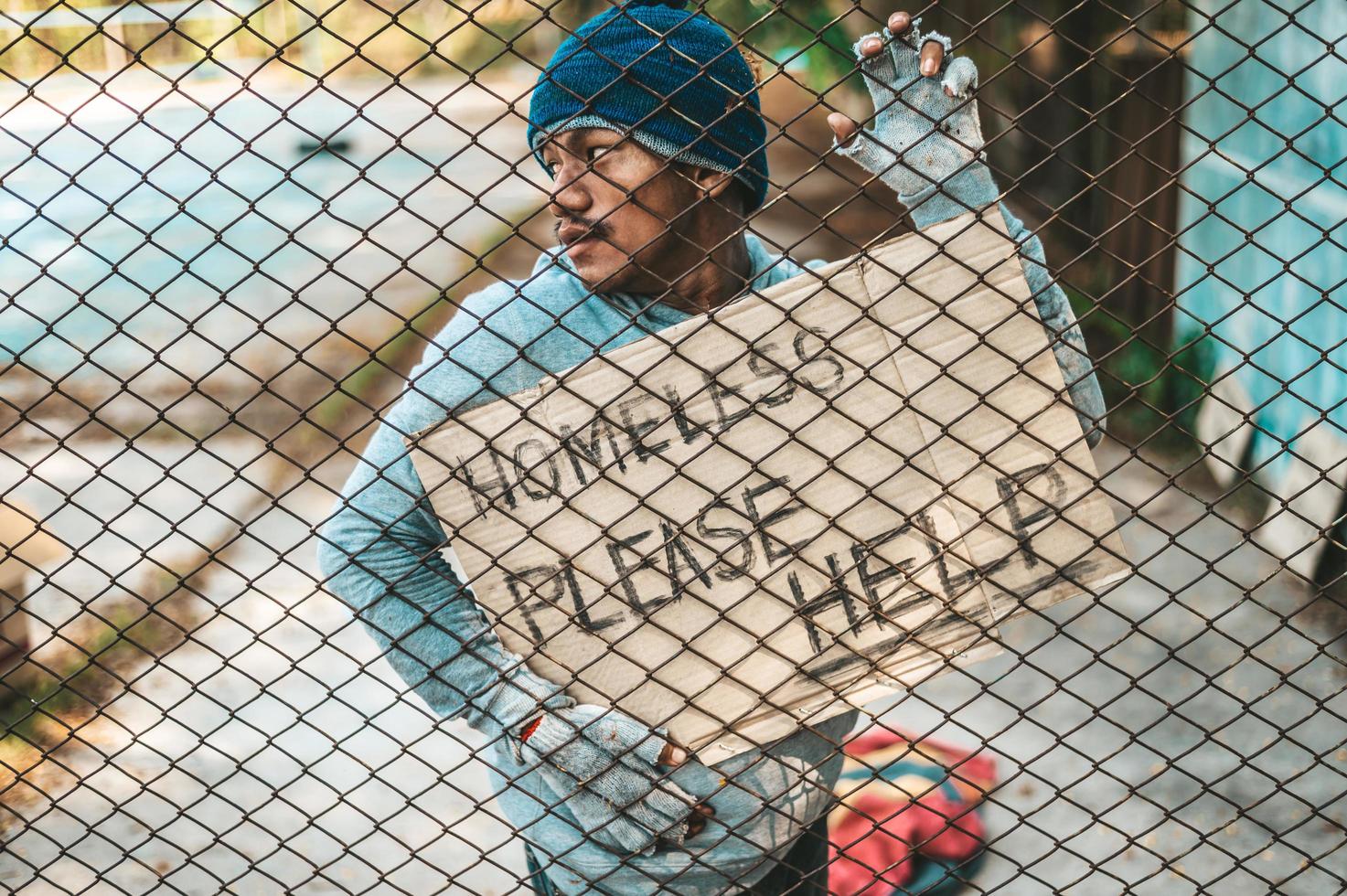 mendigos en una valla con mensajes para personas sin hogar por favor ayuden foto