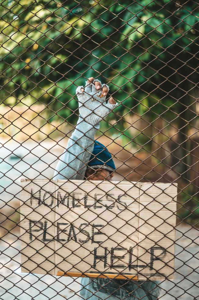 Beggars at a fence with homeless messages please help photo