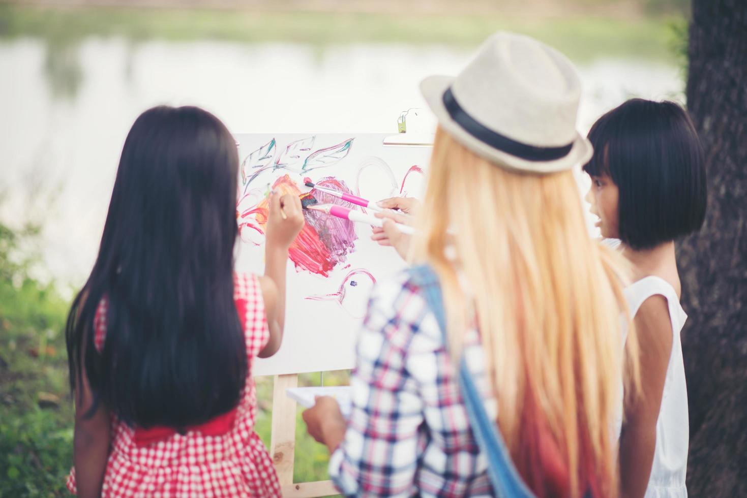 Mother and daughters drawing pictures together in a park photo