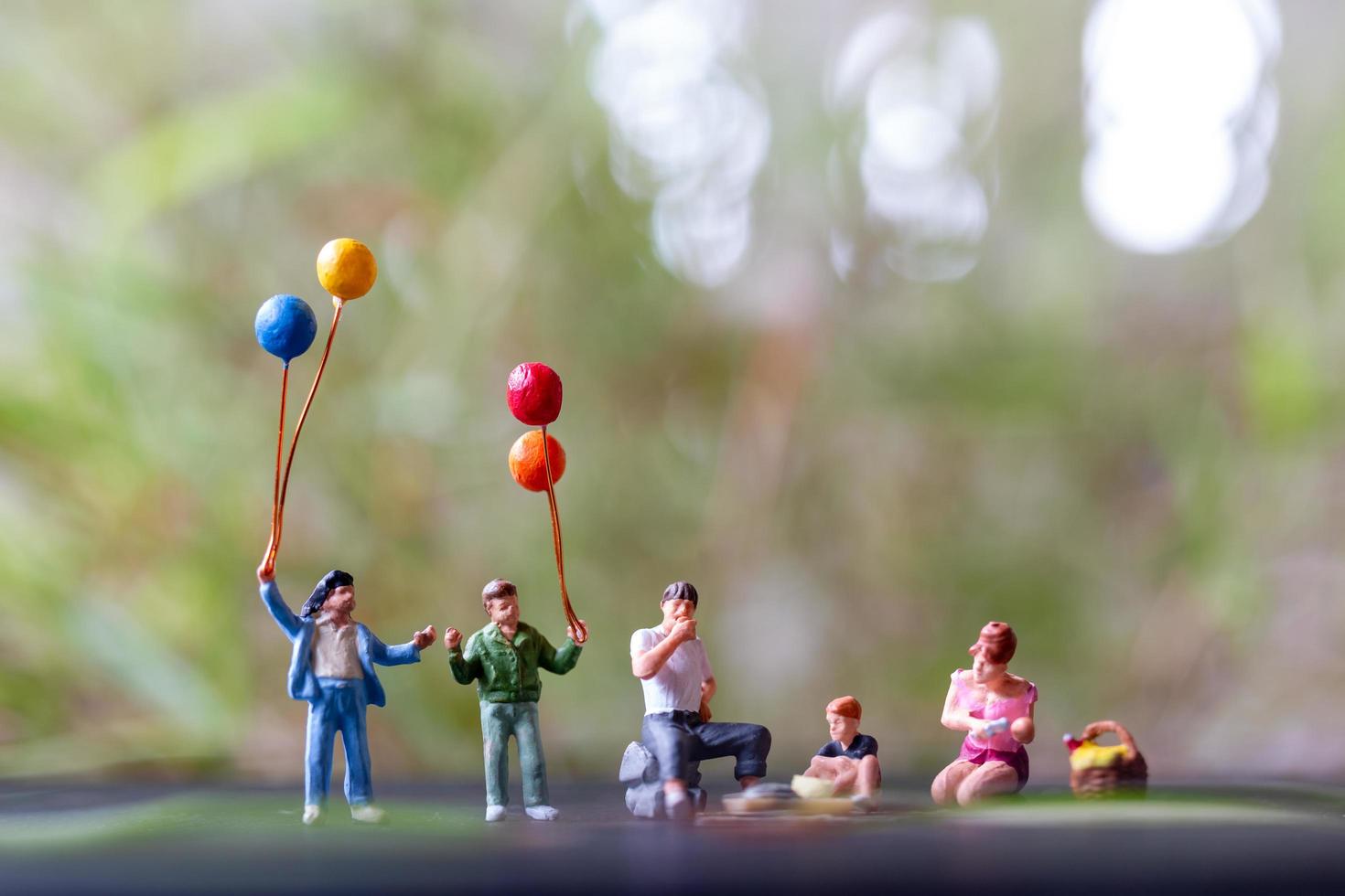 Figuras en miniatura de una familia sentada en un parque foto