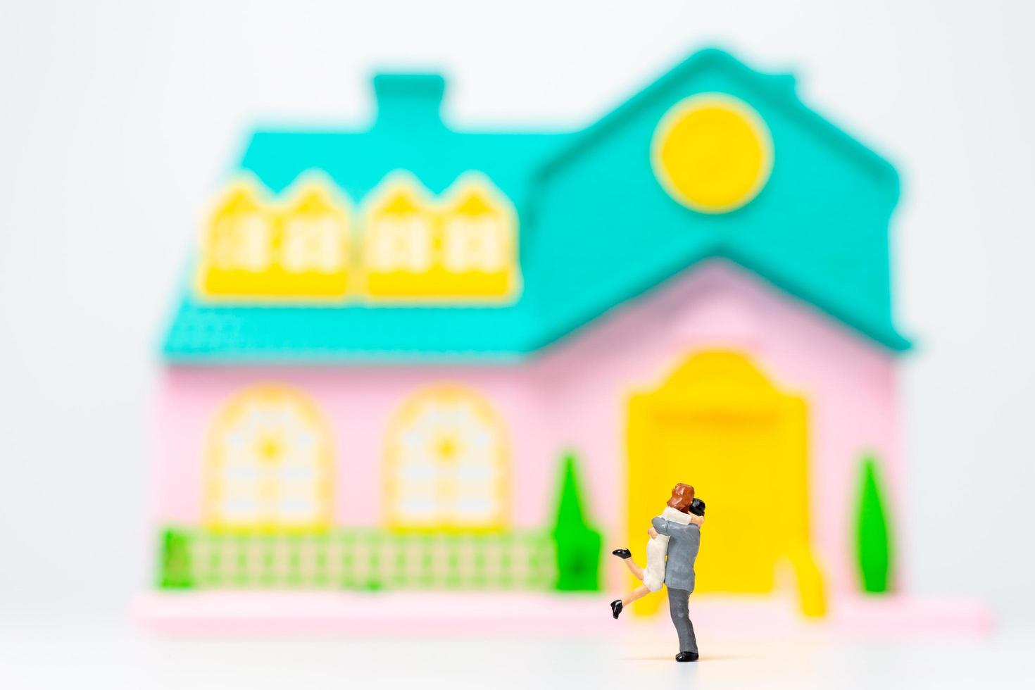 Two miniature figurine people hugging in front of a house photo