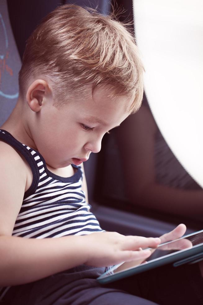 Child using tablet while traveling by bus photo