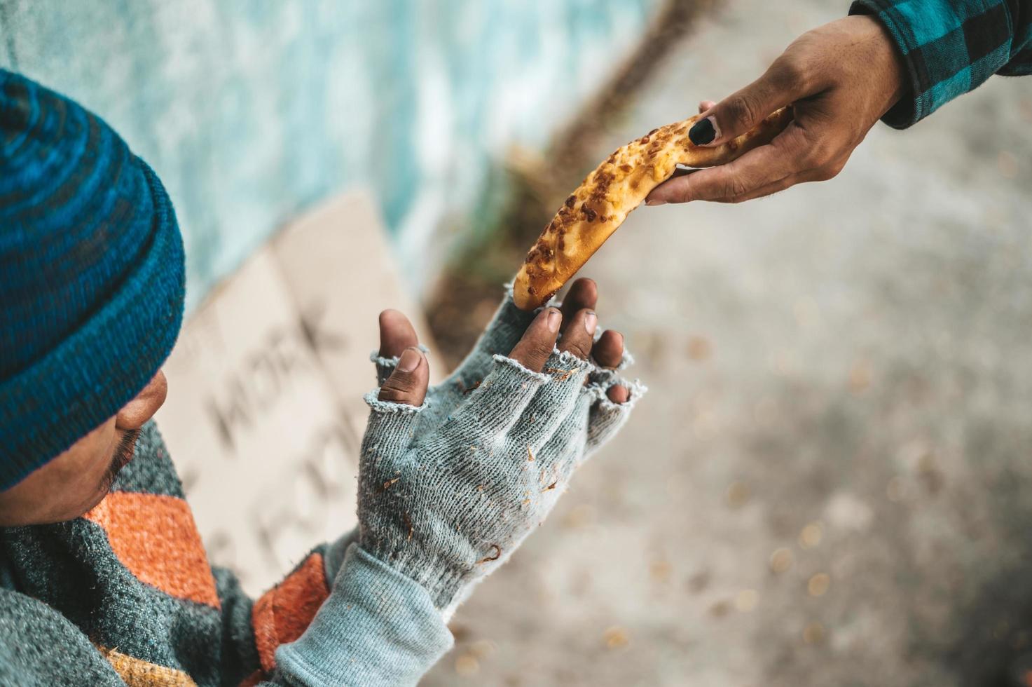 The bread-maker gives to a beggar on the side of the road photo